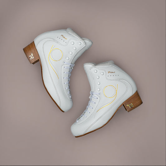 disport white figure skate boots with gold swirls and brown leather heels adorned with rhinestones on a beige background